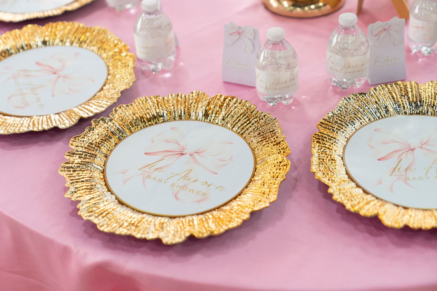 Elegant white and gold scalloped paper plates with metallic trim arranged on a pink background for a fancy party setting.