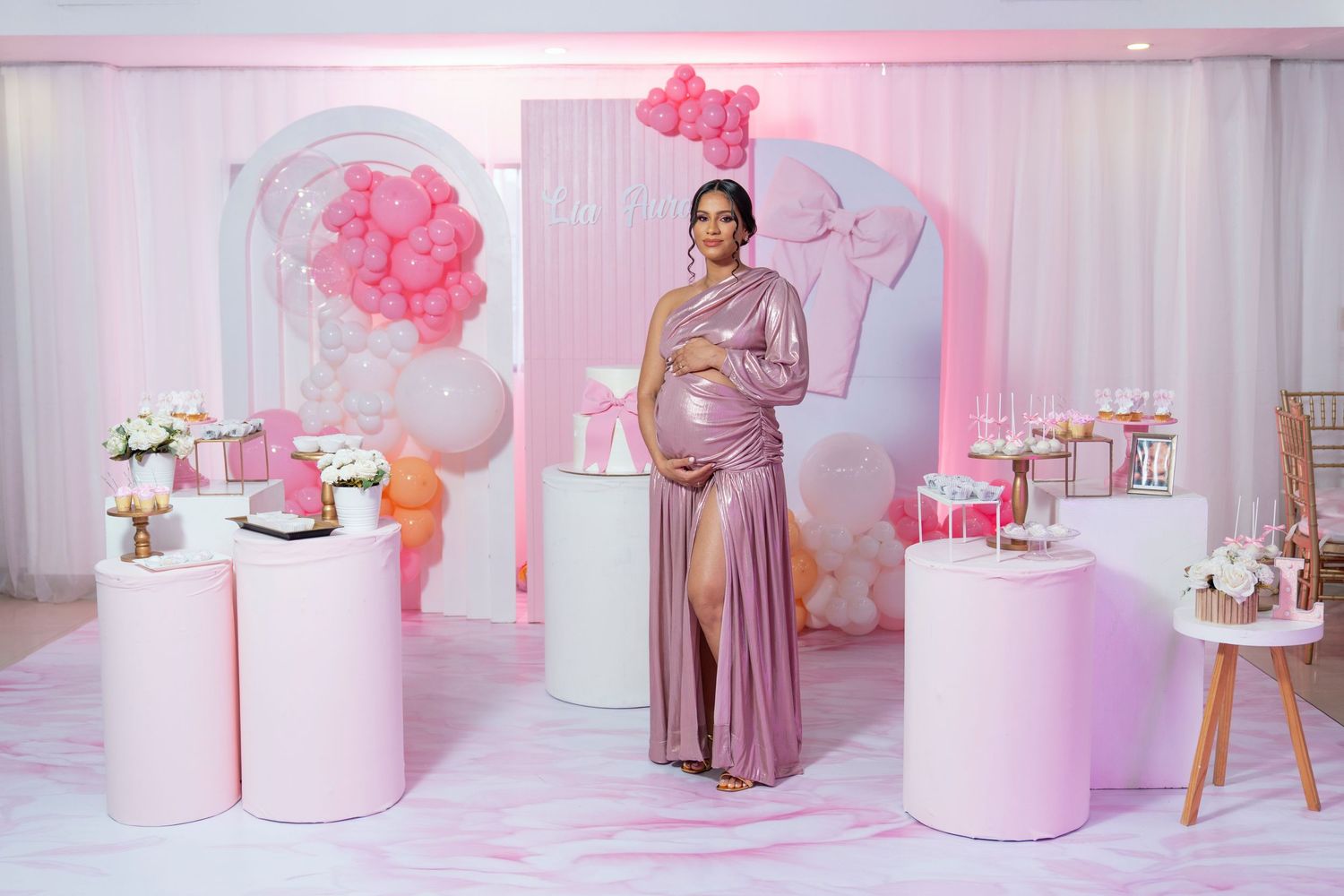 Pink and white baby shower decorations with floral arrangements and seating areas create an elegant celebration space.