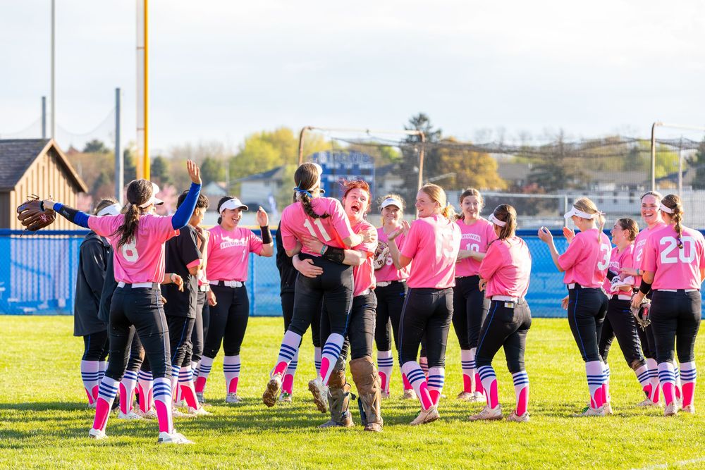 Players in pink jerseys form a circle on the sports field.