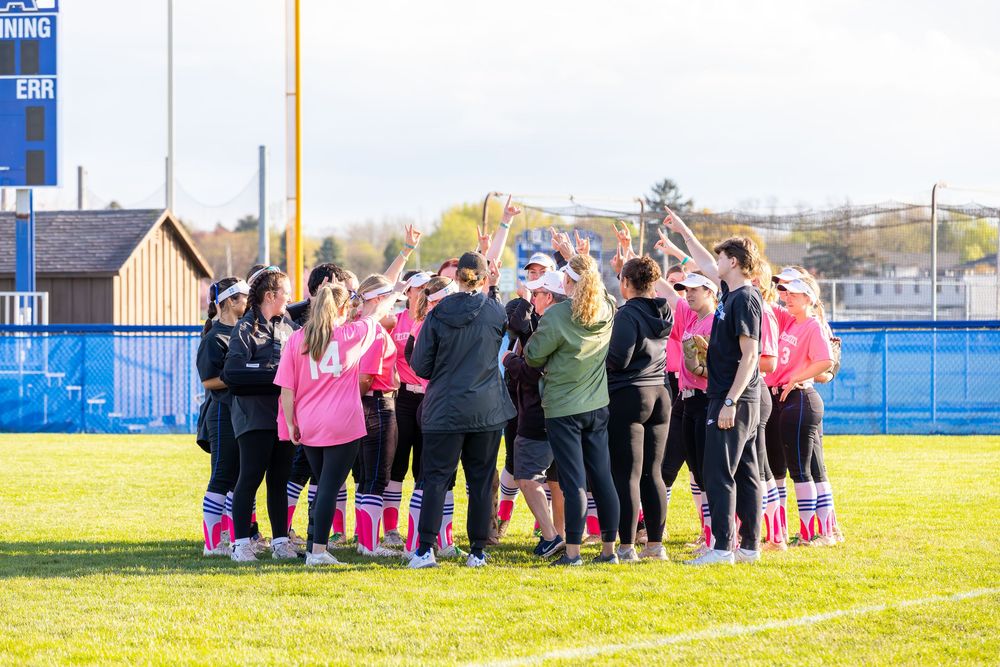 Team members gather in a huddle formation on athletic field.