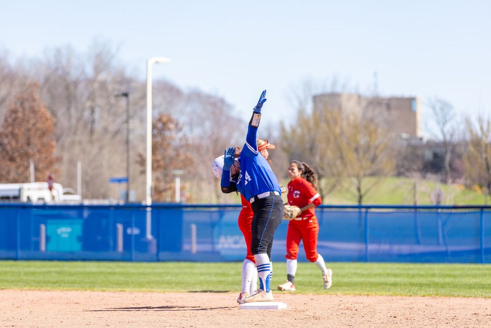 Panoramic view of softball diamond with players positioned during game action.