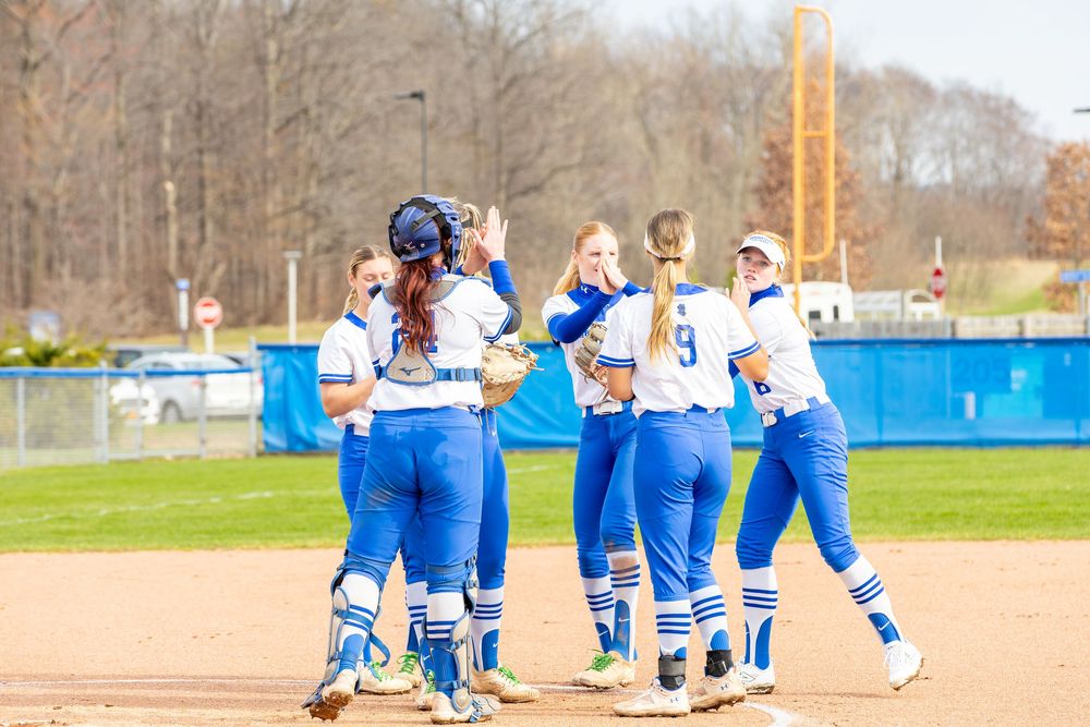 Team members gather on the softball field during a game break.