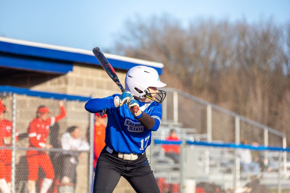 Softball players in action during a competitive game on a sunny spring day.