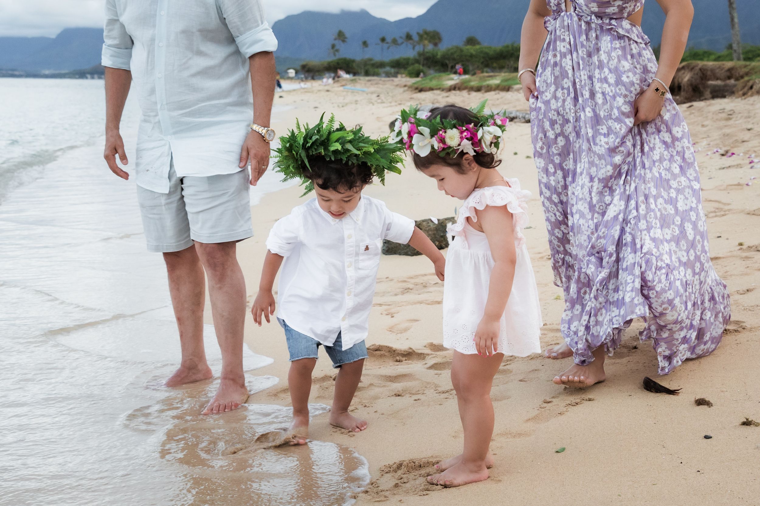 Family walking together along the shoreline at a Hawaiian beach.