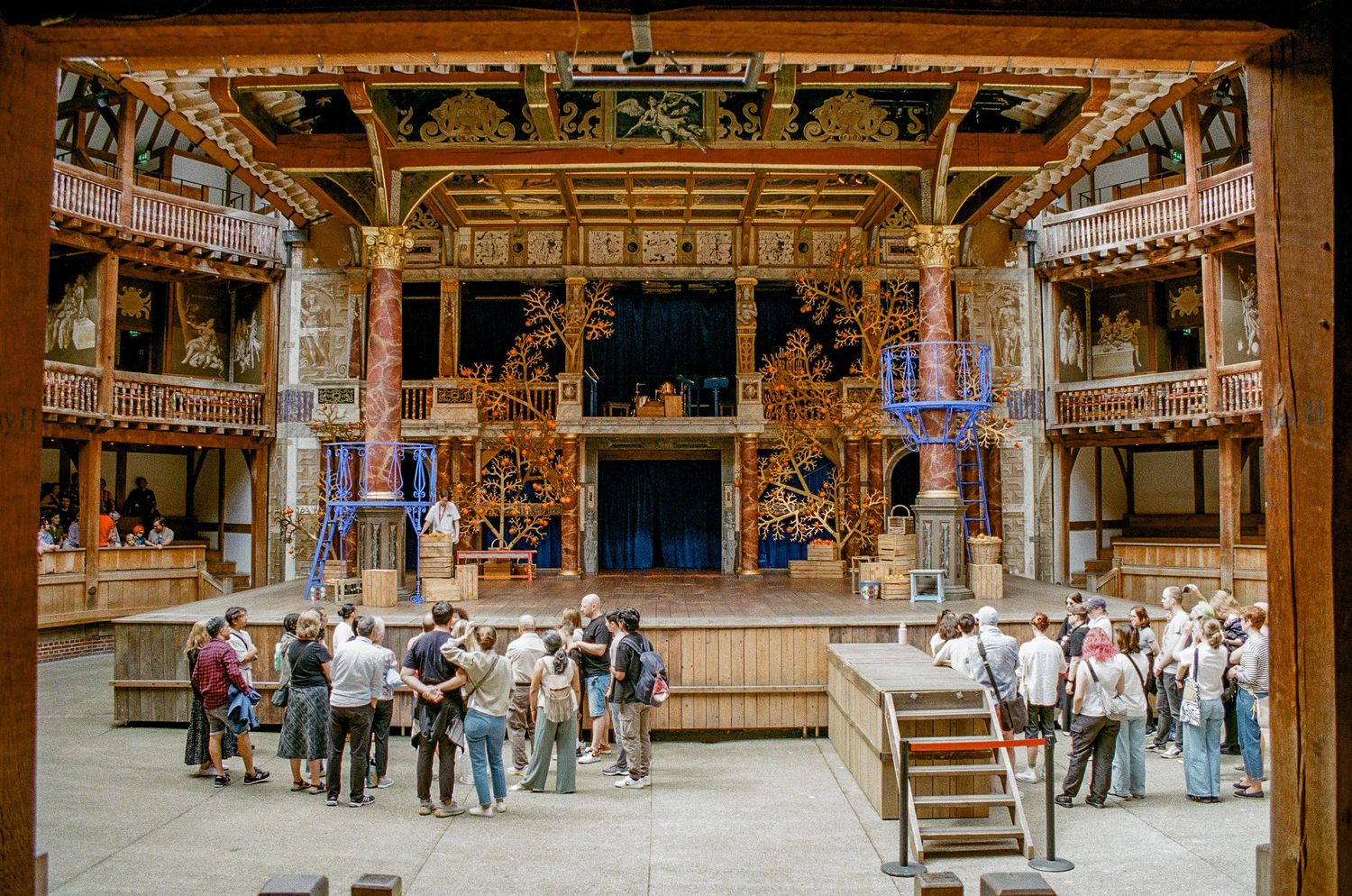 Interior view of Shakespeare's Globe Theatre in London showing the ornate wooden stage and multiple gallery levels.