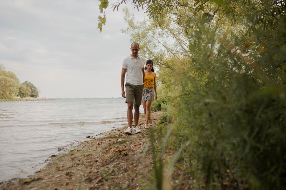Couple walk on the shoreline of Lake Ontario. Kingston, On, Ca