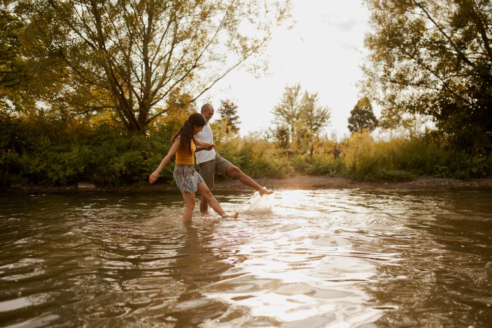 Couple splashes in Lake Ontario. Sun catches the water spray. Kingston, On, Ca.