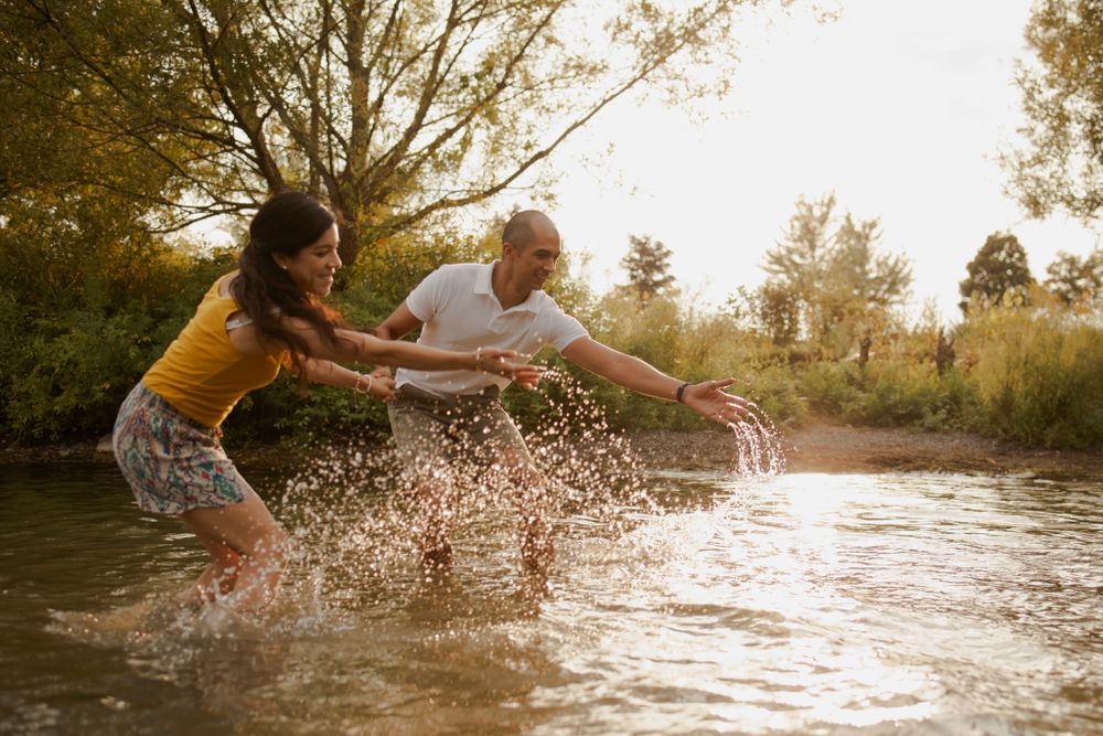Couple splashes in Lake Ontario. Sun catches the water spray. Kingston, On, Ca.