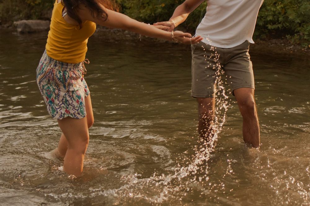 Couple splashes in Lake Ontario. Sun catches the water spray. Kingston, On, Ca.