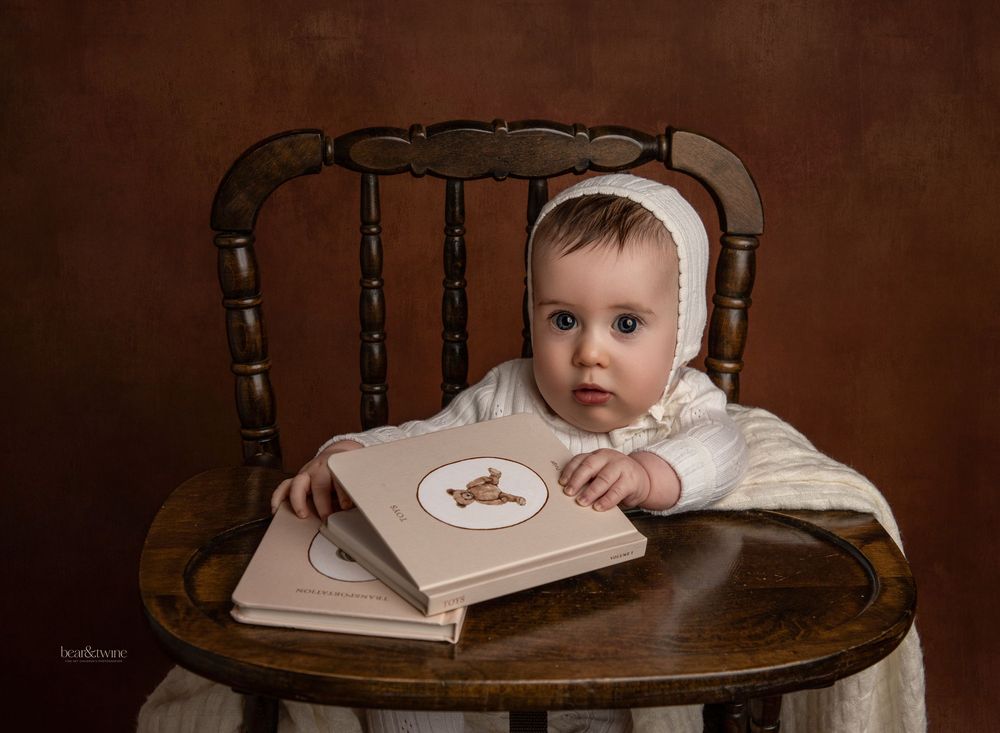 Fine art portrait of baby holding vintage books.