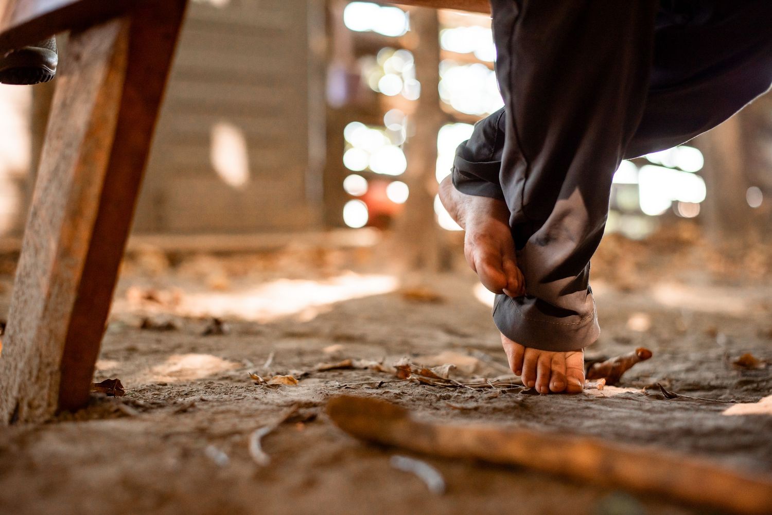 Close-up view of a worker's gloved hand scraping old insulation material from a dusty attic floor.