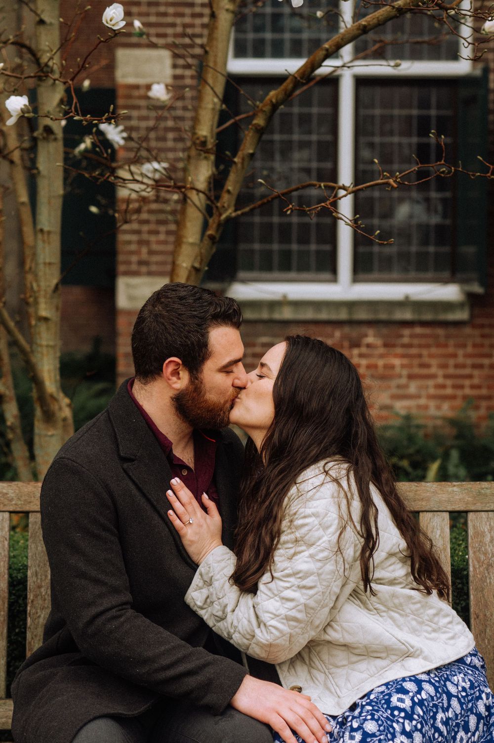 A tender moment shared on a garden bench beneath flowering spring trees.
