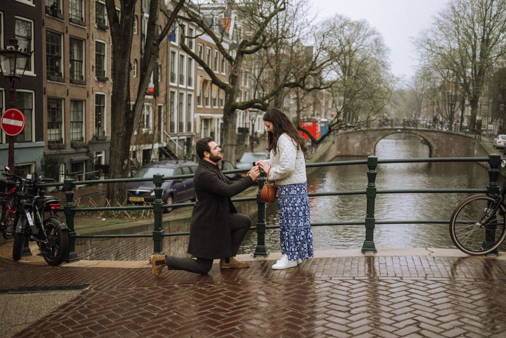A happy couple during a secret proposal on an iconic Amsterdam bridge.