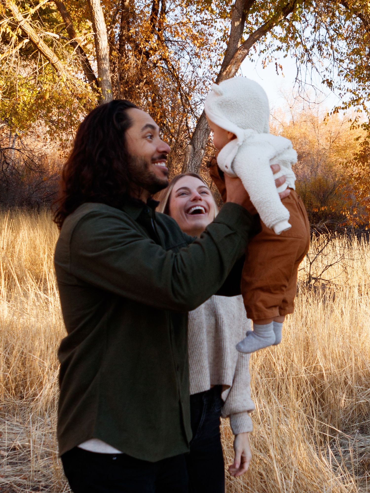 Joyful family moment shared together outdoors in a golden autumn field during sunset.