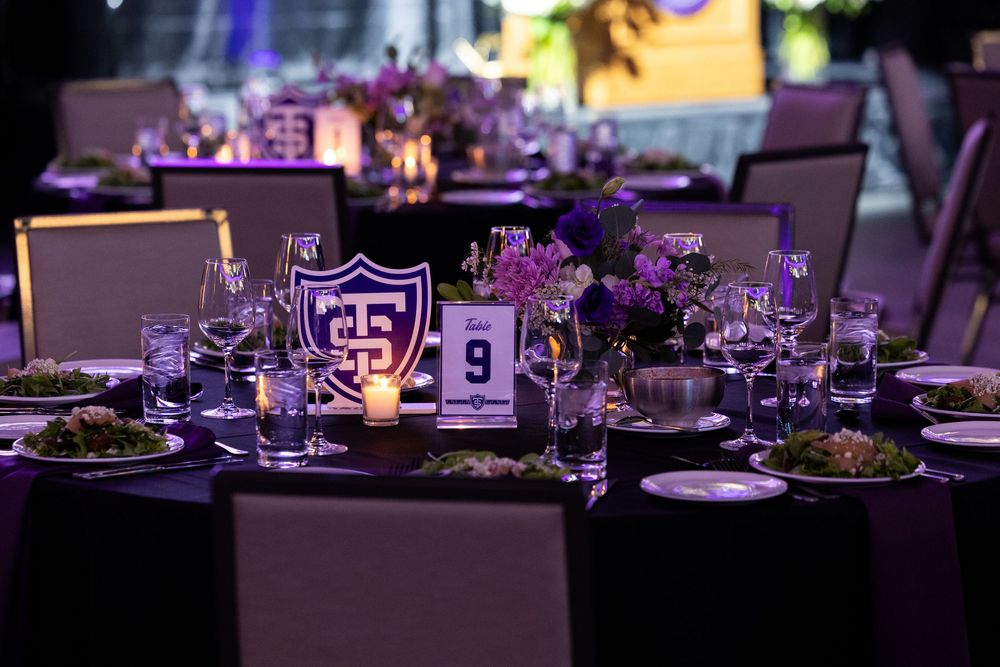 Elegant wedding reception tables decorated with purple lighting, floral centerpieces and formal place settings.