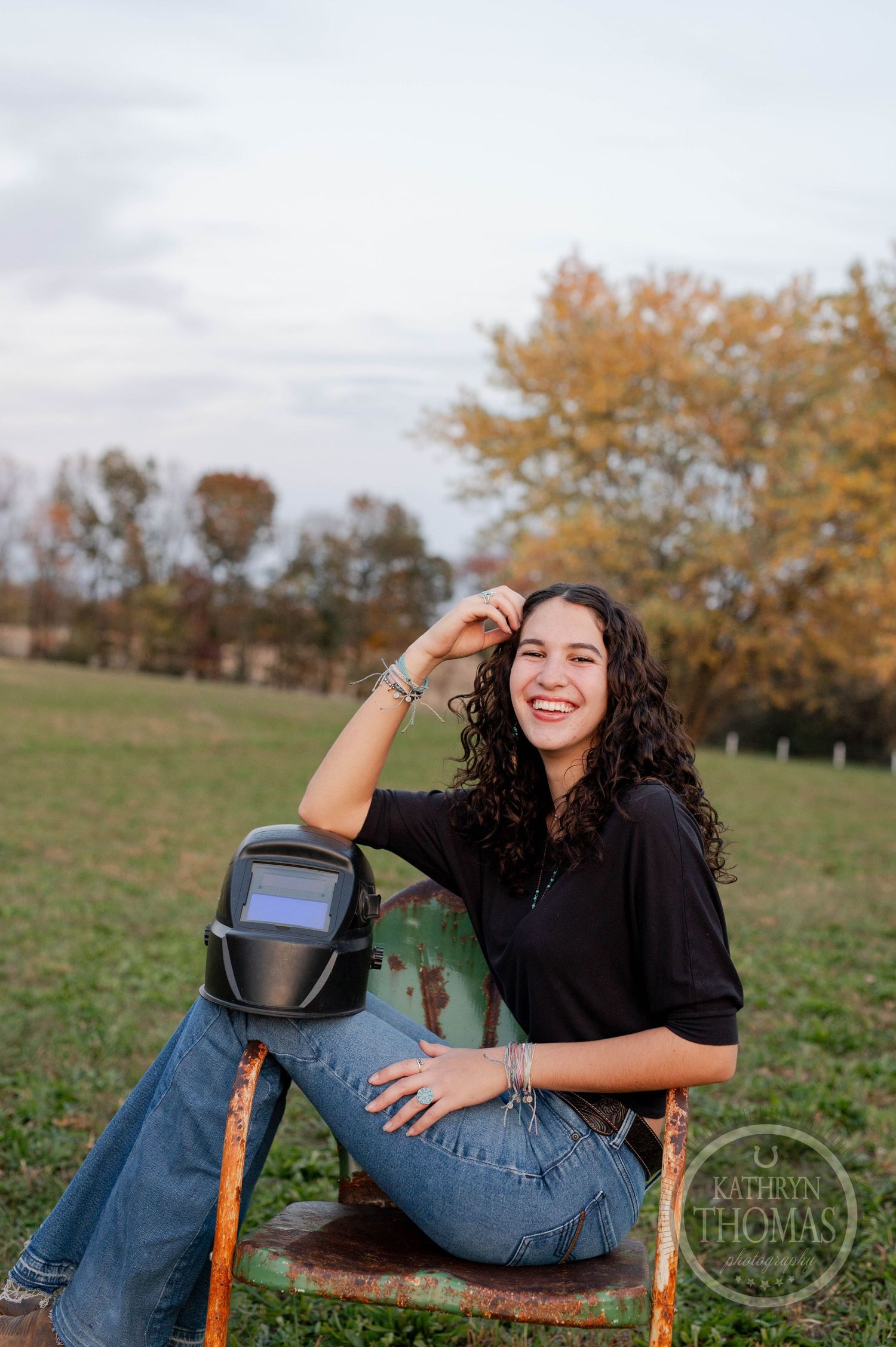 Candid outdoor portrait with welding gear and autumn trees in the background at sunset.