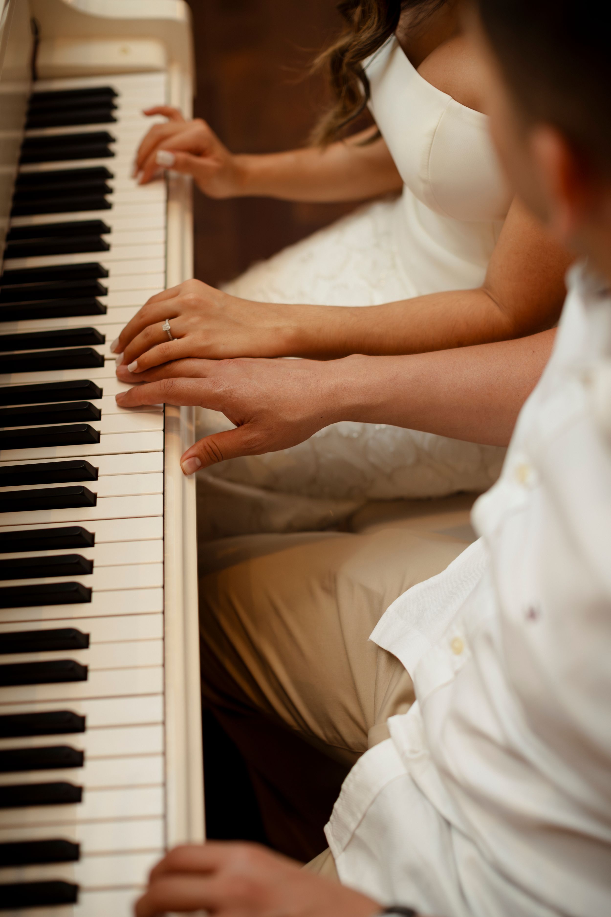 Close-up view of hands playing piano keys in a warm-toned setting showing multiple angles of performance.