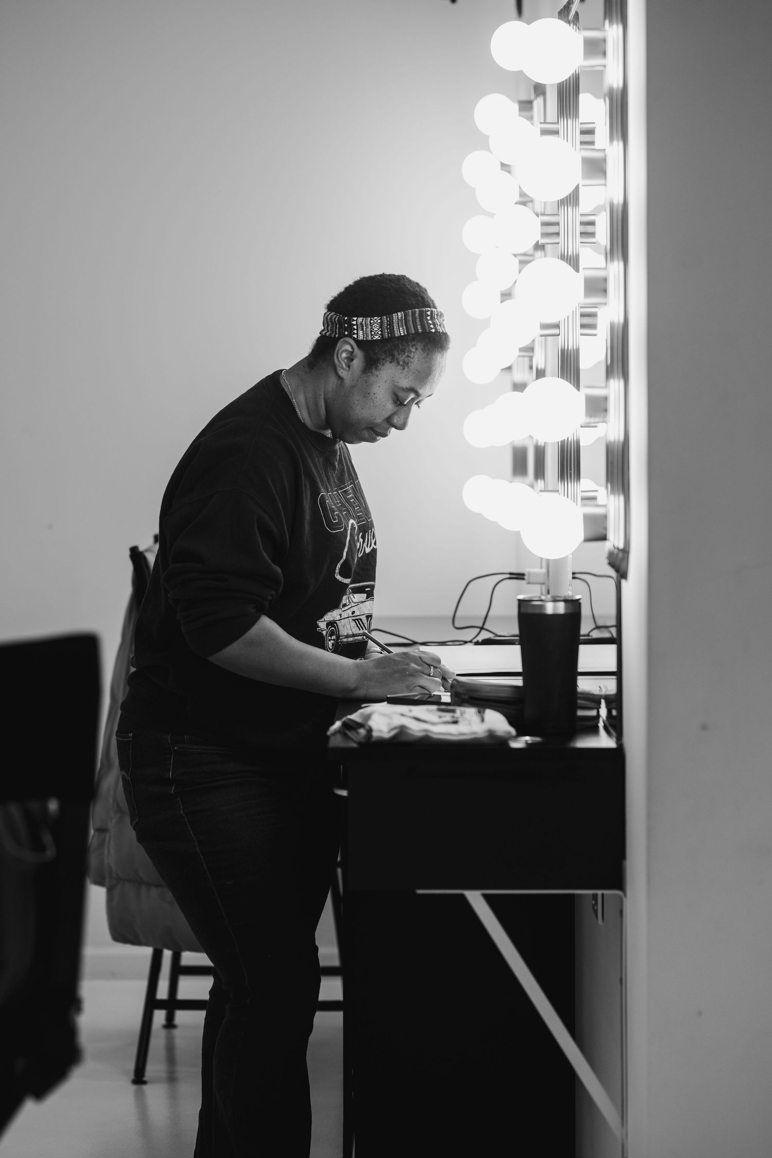 Person working at desk near illuminated vanity mirror in dark room.