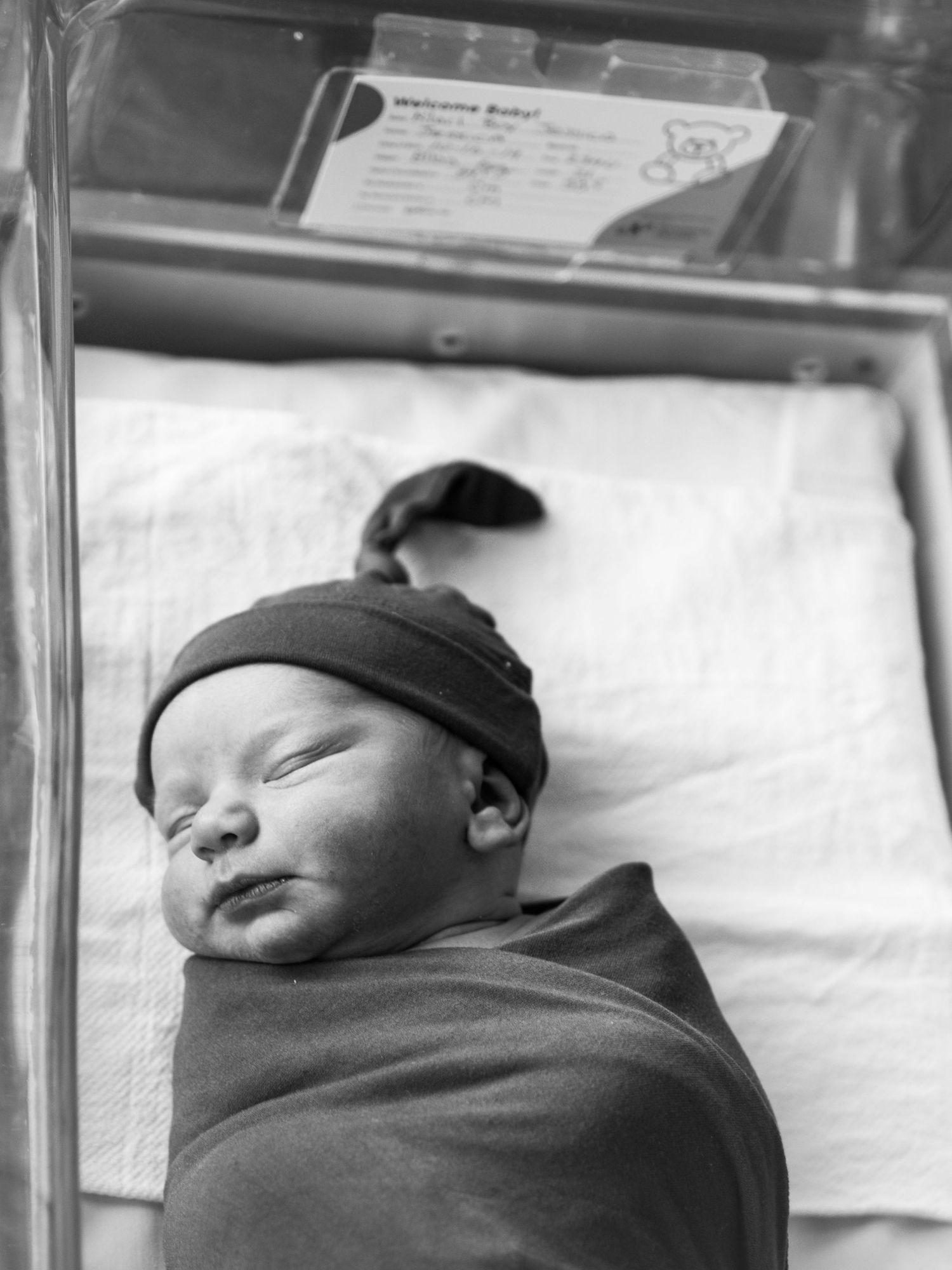 Black and white series of a newborn baby swaddled and sleeping peacefully.