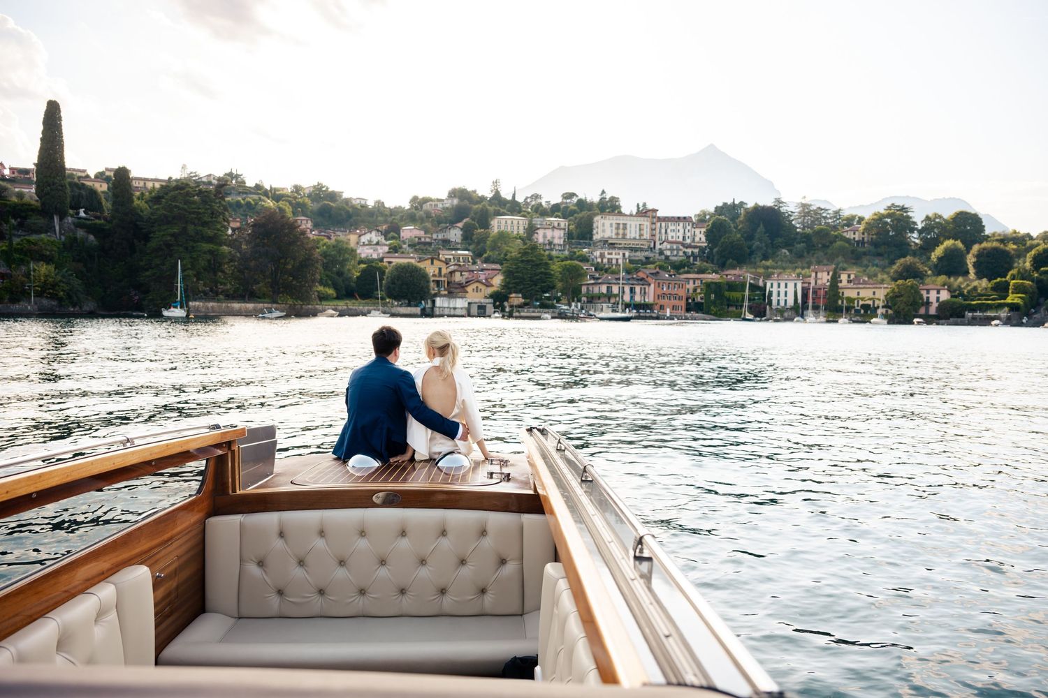 Person sitting on a luxurious boat while cruising along the scenic coastline of Lake Como, Italy.