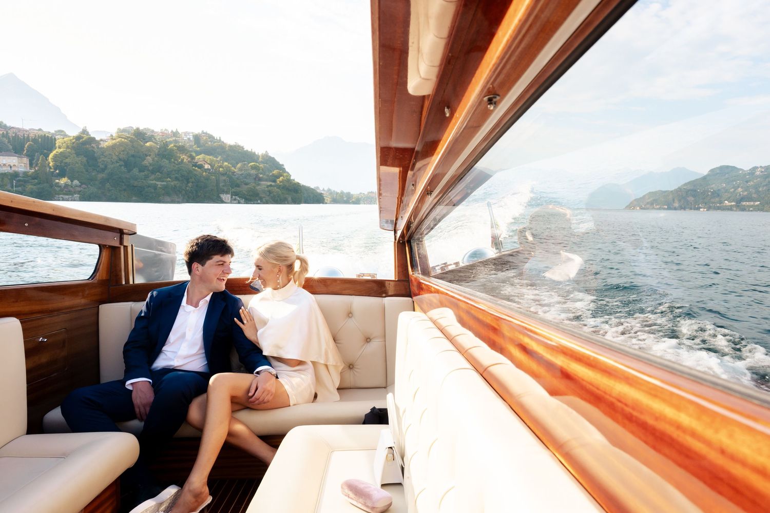Luxury yacht interior with wood paneling and ocean views through large windows during daytime sailing.