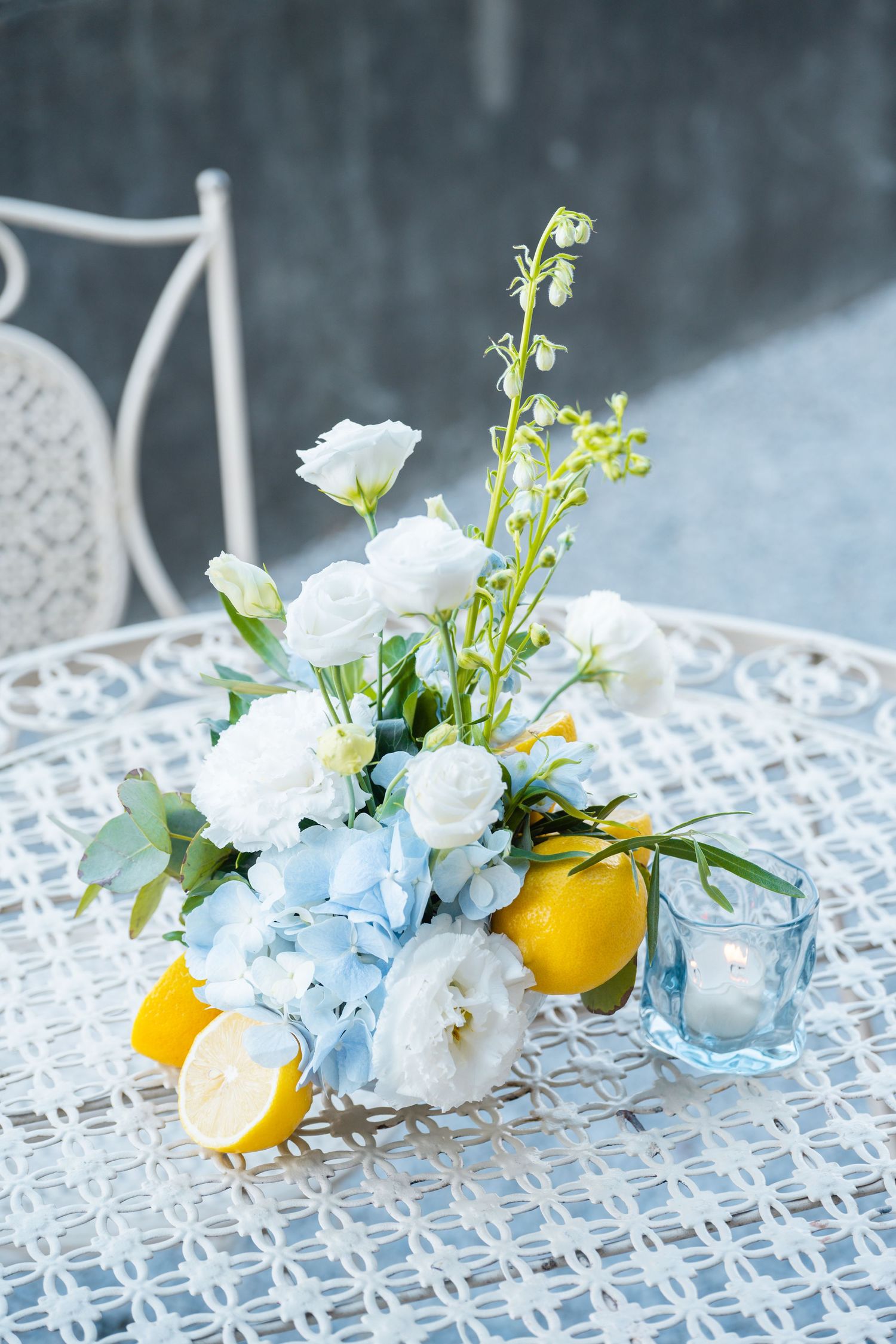 Delicate blue hydrangeas and yellow lemons arranged on white lattice create a fresh spring table setting.