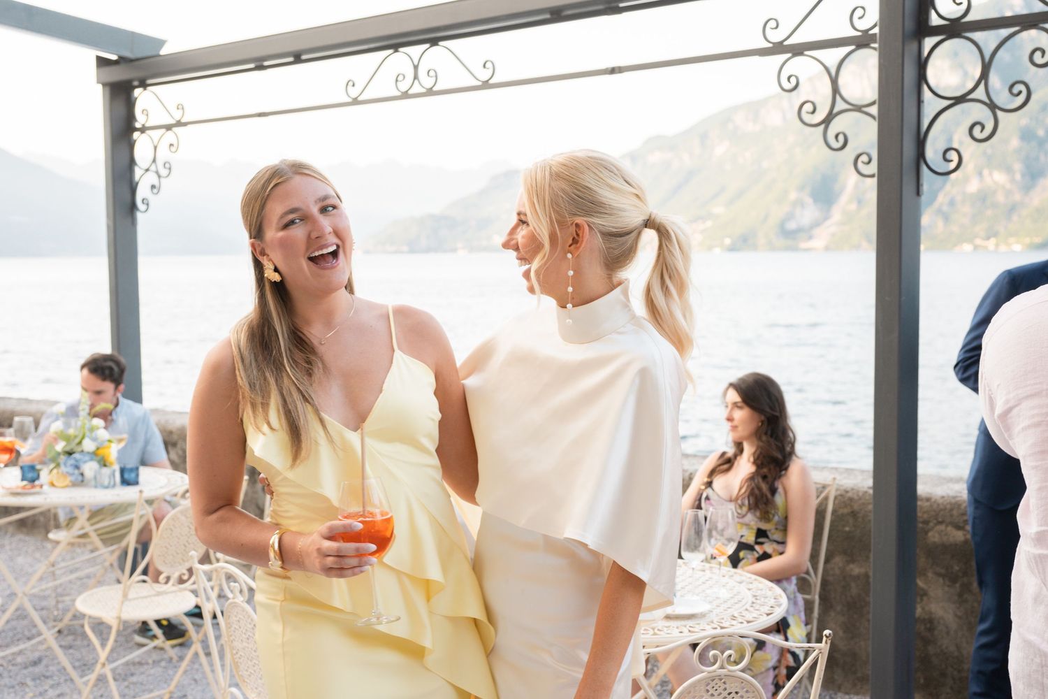 A group of people enjoying drinks and conversation at an elegant outdoor patio restaurant setting.