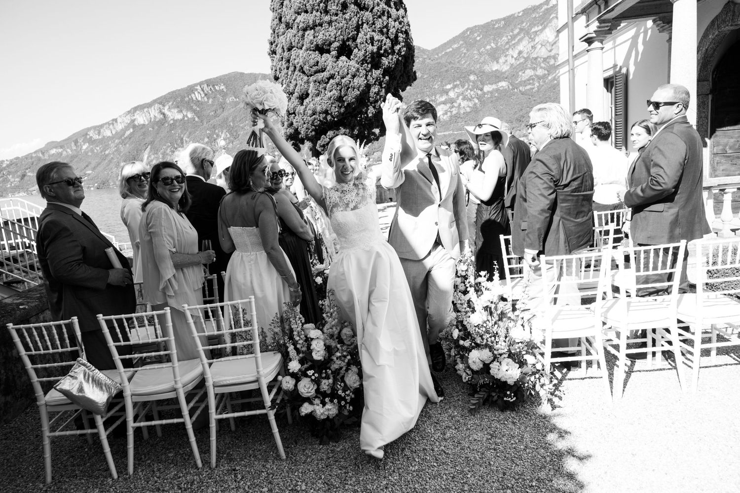 Wedding party walking in a line through an outdoor garden setting during a summer celebration.