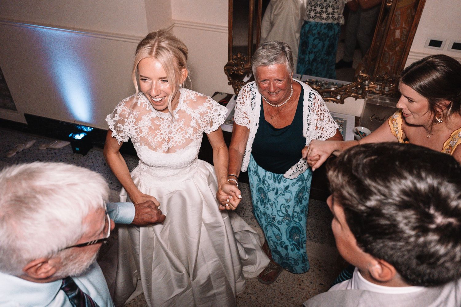 Dancers moving across a brightly lit dance floor during a festive celebration with guests watching.