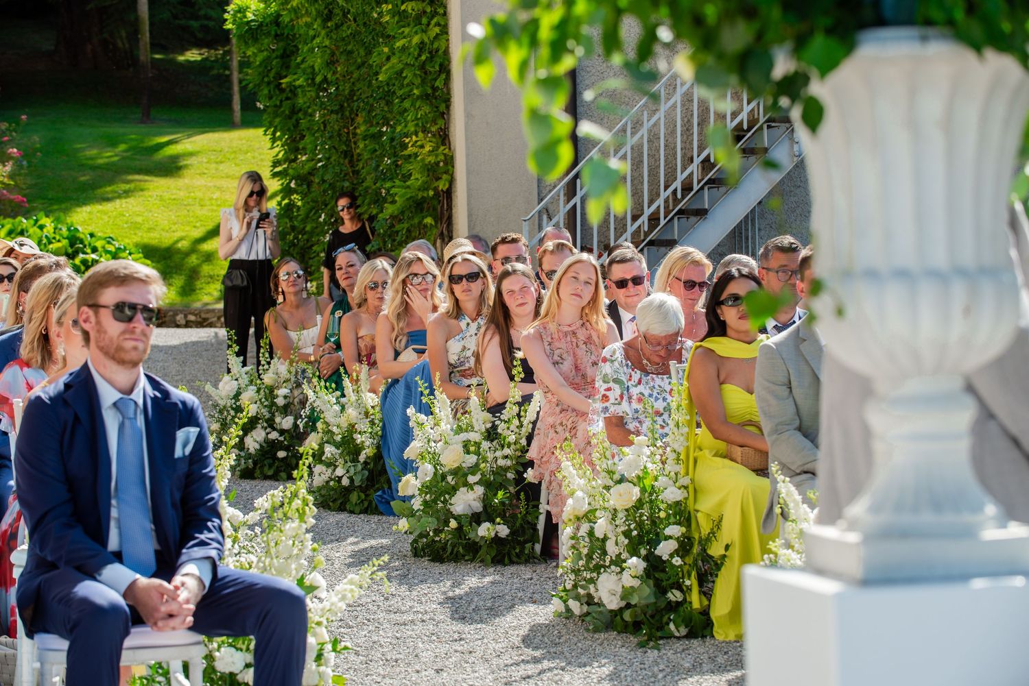 Wedding guests mingle and socialize in an elegant outdoor garden setting during a summer celebration.