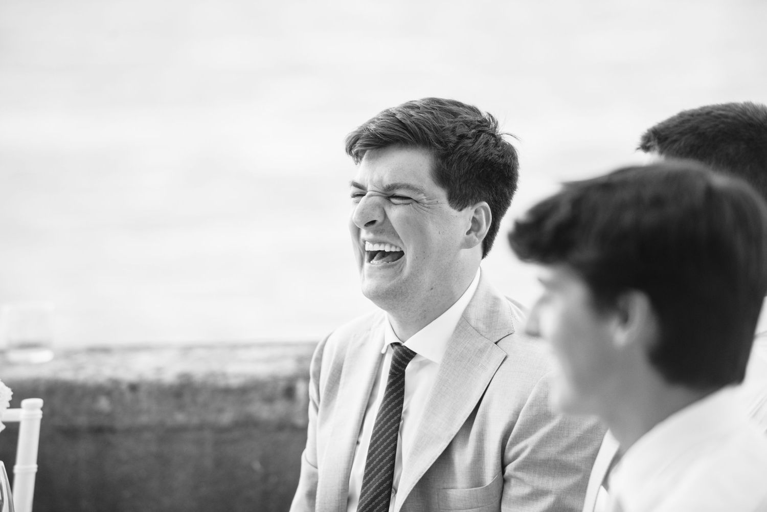 A joyful moment captured in black and white as people share laughter at an outdoor gathering.