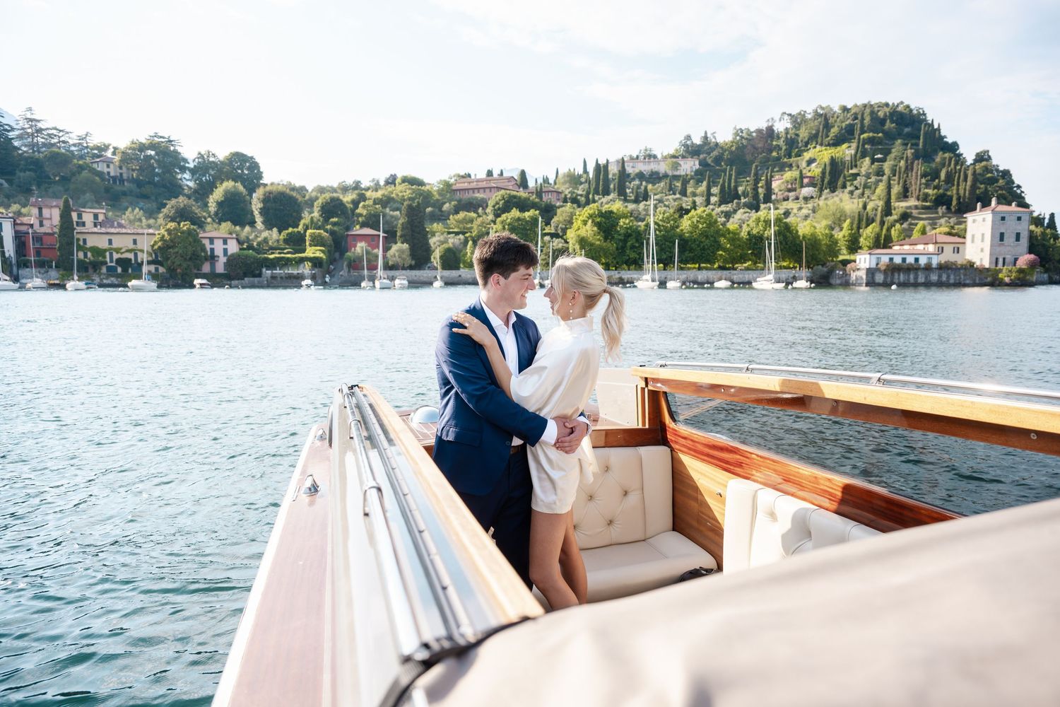Couple enjoying a romantic boat ride on Lake Como with scenic Italian villas and mountains in the background.