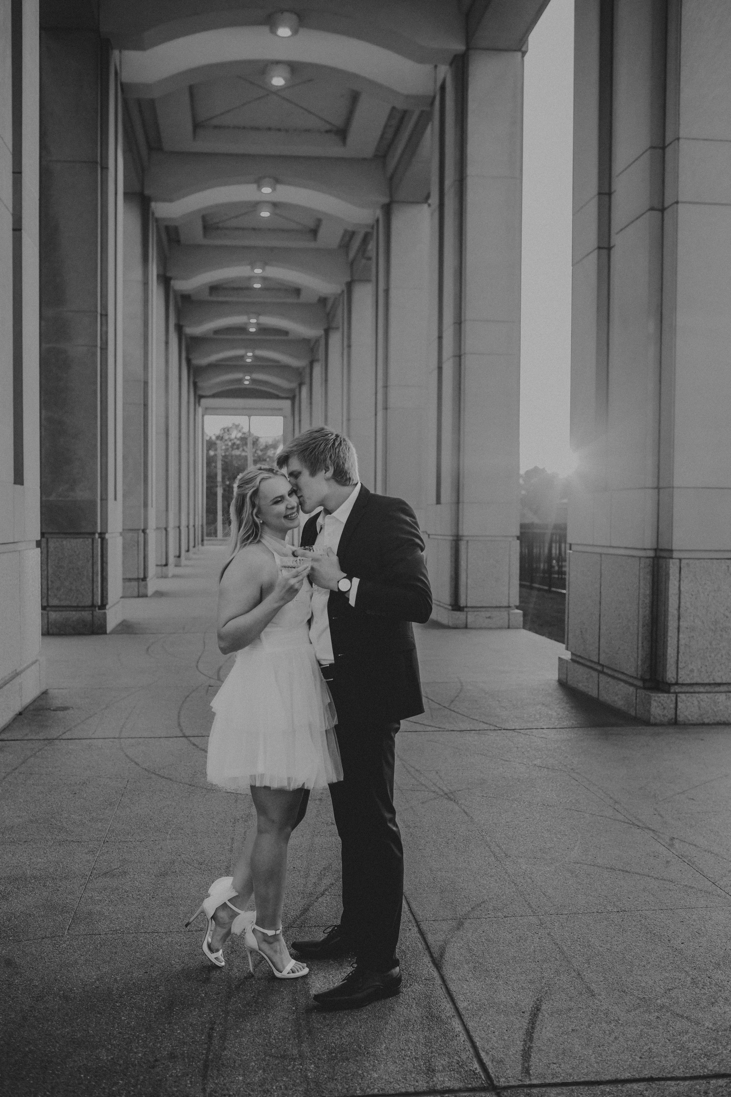A tender black and white photo series showing a small child and adult sharing a sweet moment in a covered walkway.