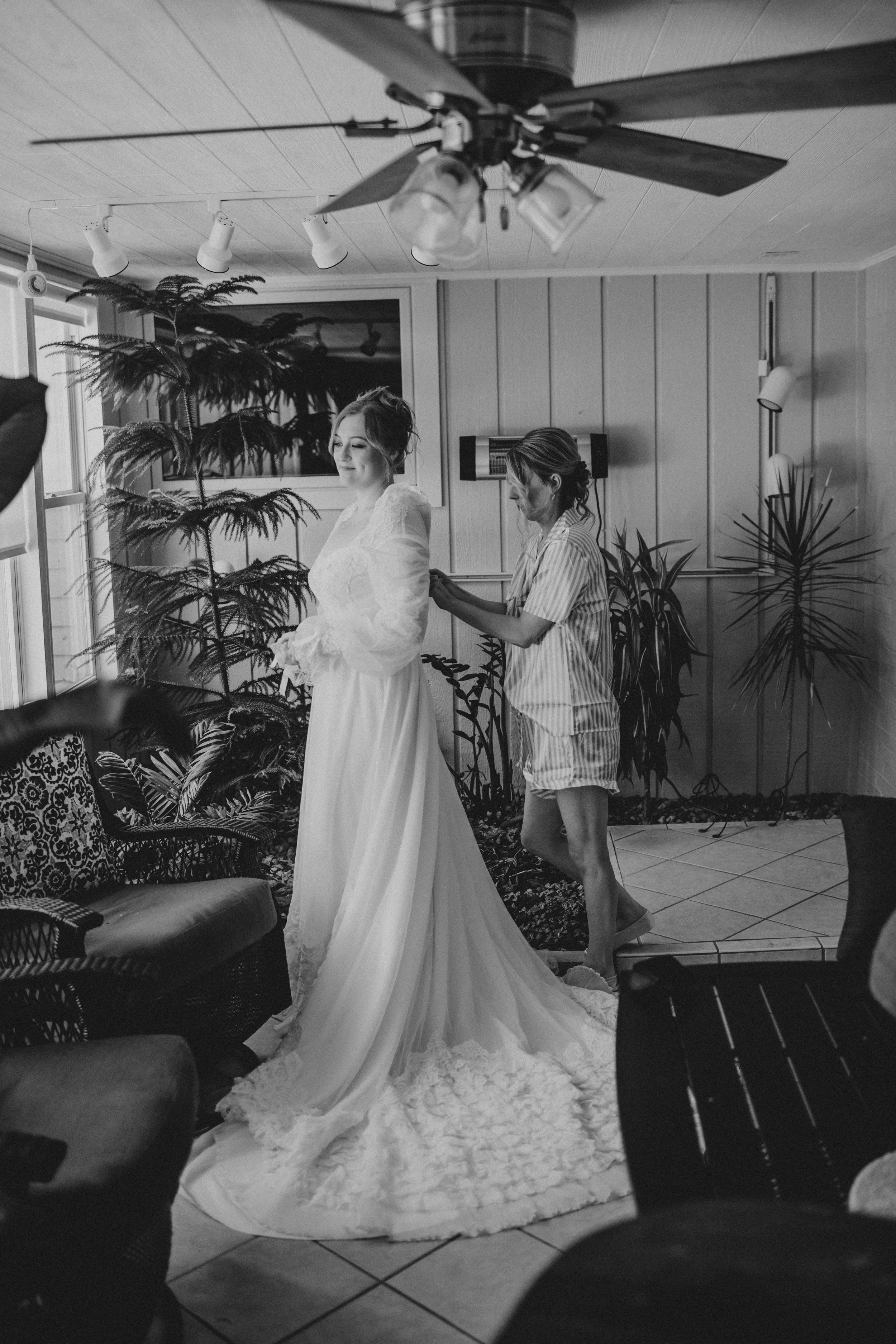 Black and white photo series showing a wedding dress with a dramatic train in an interior space with tropical plants.