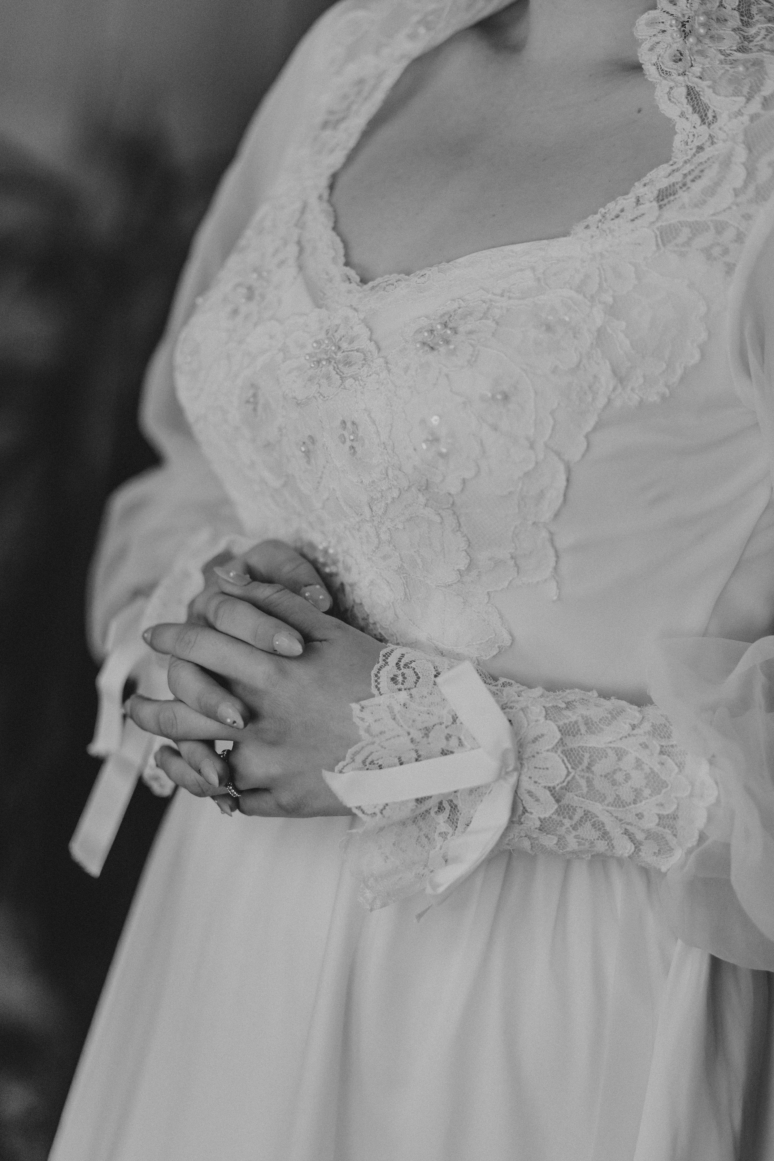 Close-up details of a delicate white lace wedding dress with intricate embroidery patterns.