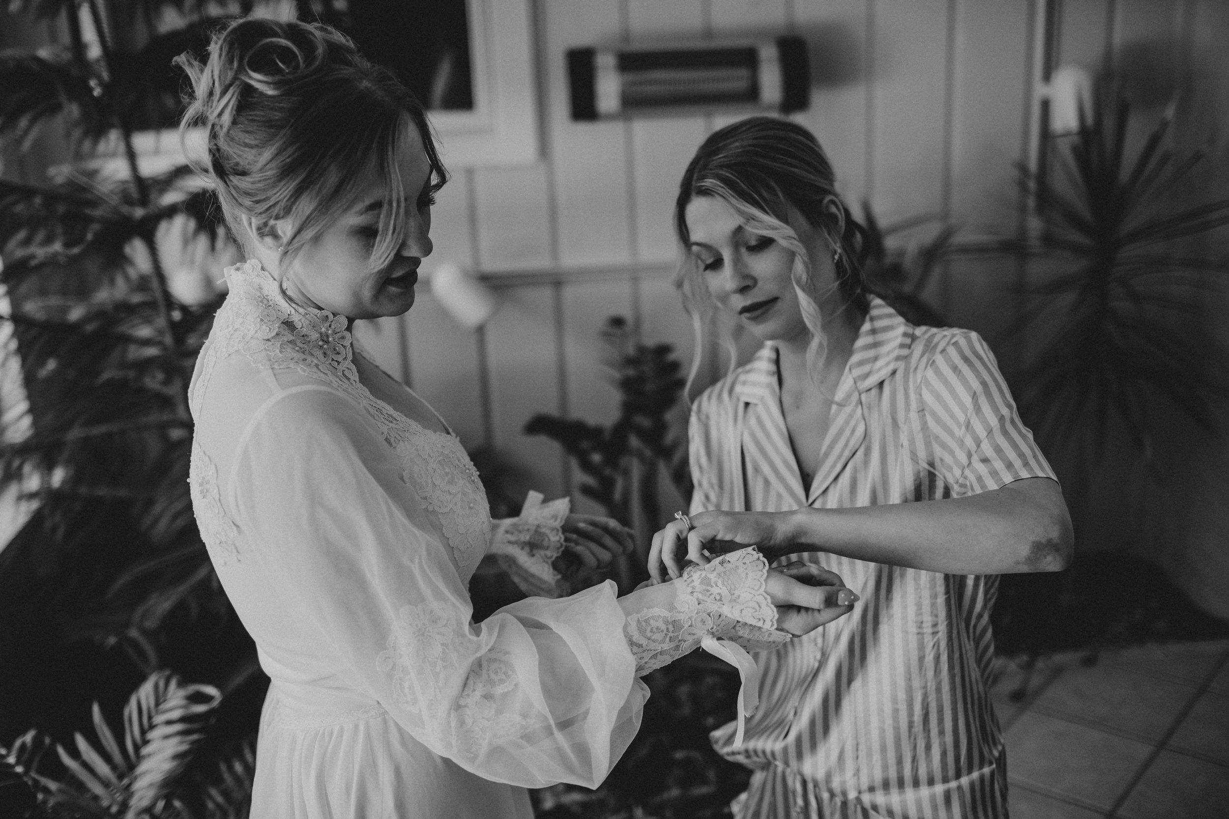 Black and white photo of a bride getting ready on her wedding day with floral bouquet.