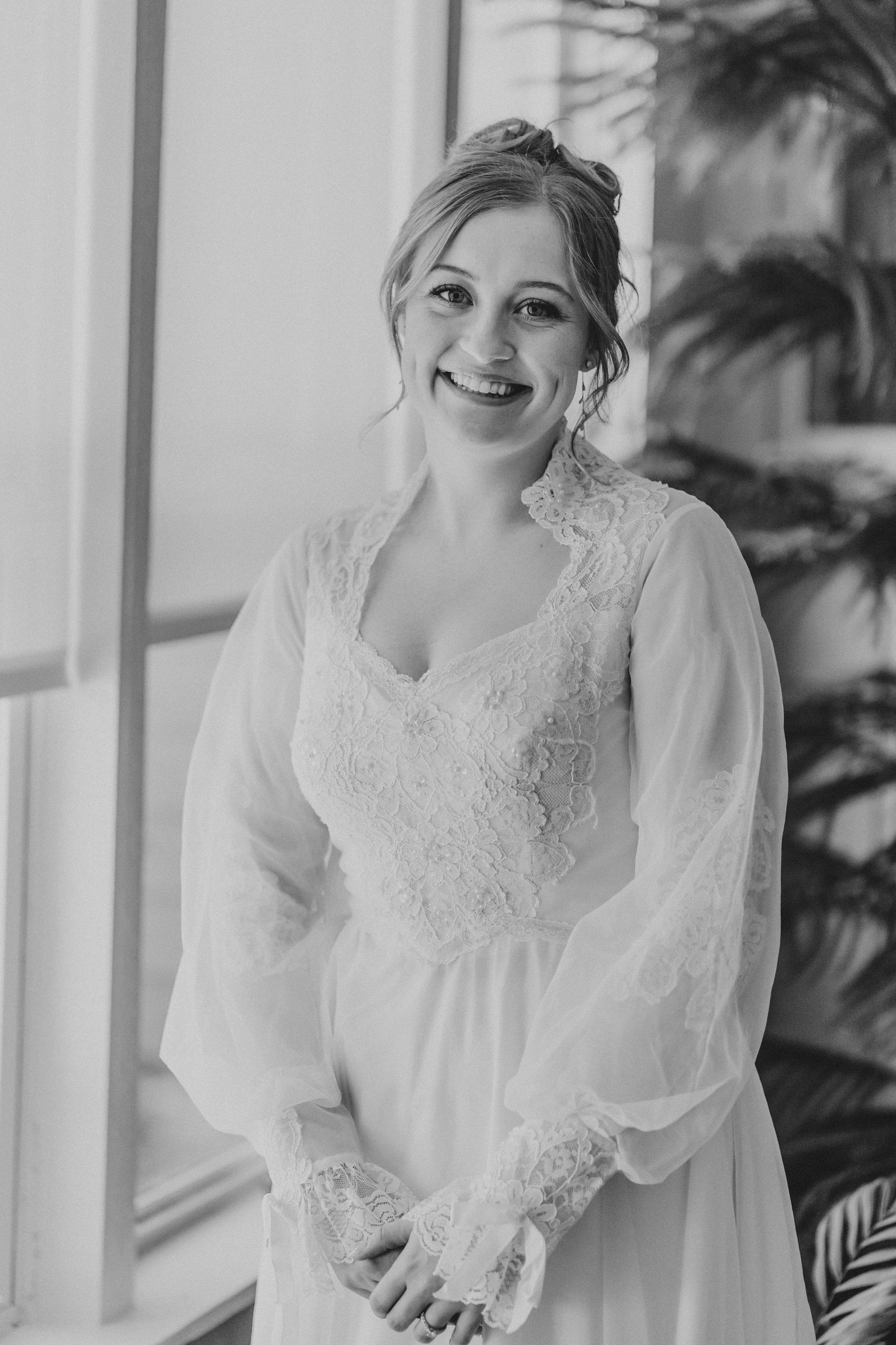 Black and white portrait showing a vintage-inspired white lace dress with billowing sleeves.