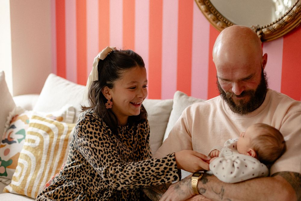 Family sharing intimate bonding moments on a couch with soft lighting and striped background.