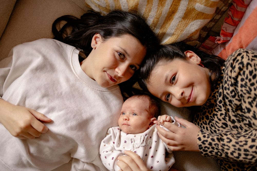 Tender family moment captured in warm tones as they lay together on cushions.
