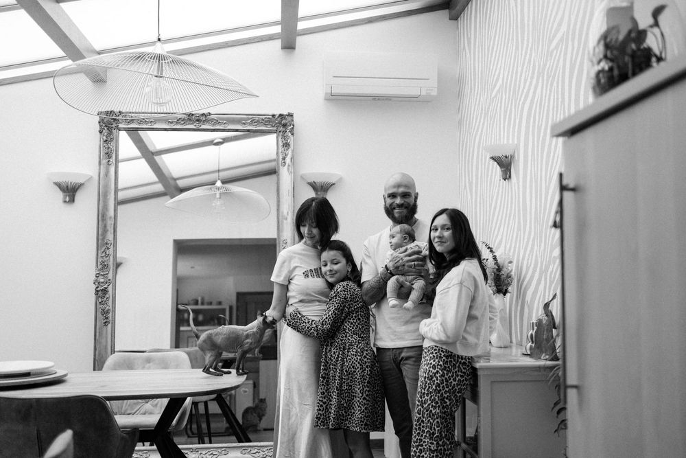 Family gathered in a bright white room with natural light streaming through windows.
