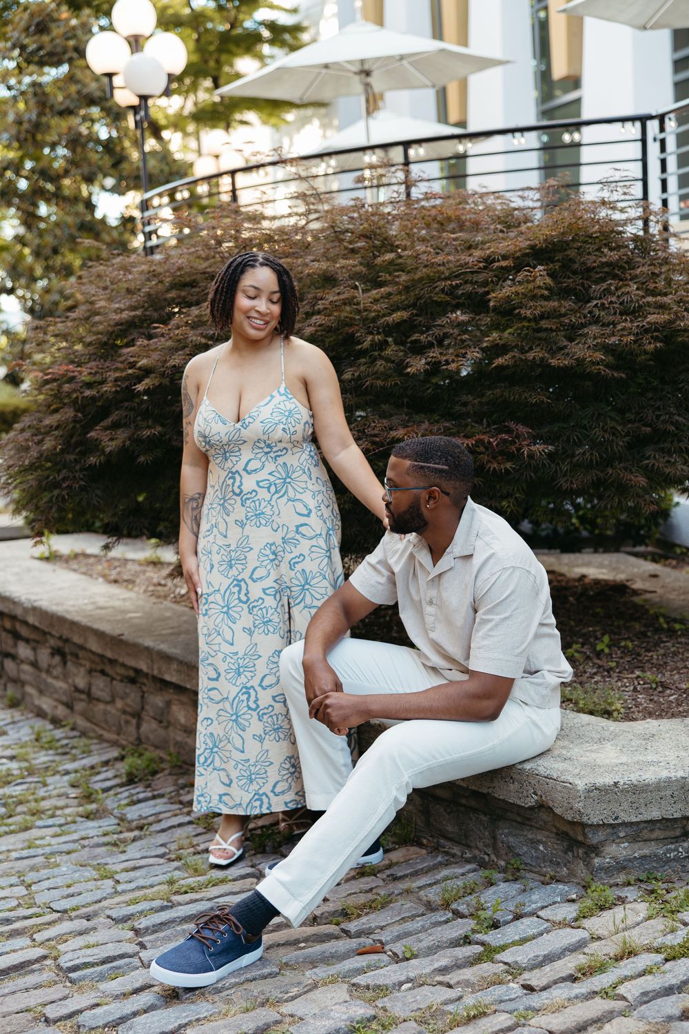 A couple sitting together on stone steps outdoors, wearing coordinated blue and white summer outfits.