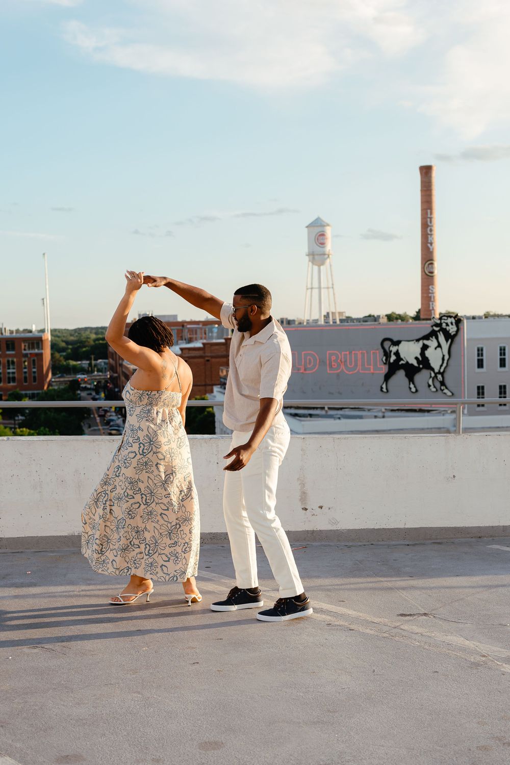 A couple dances together on an urban rooftop with a water tower and industrial buildings visible in the background.