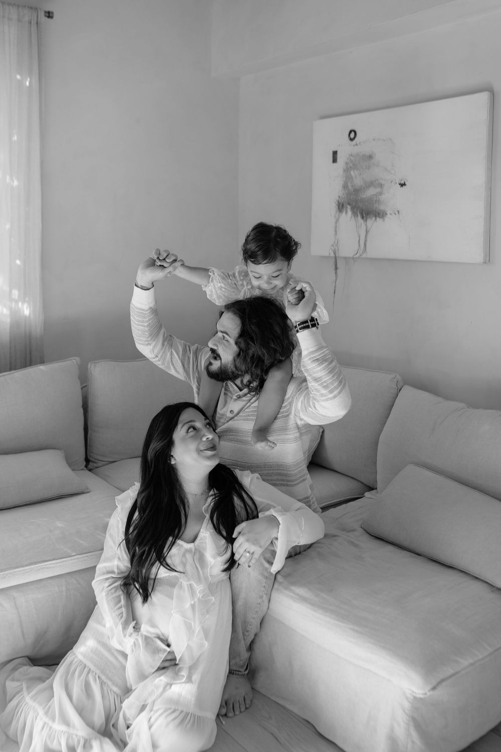Playful moments captured on a white couch in a minimalist interior setting.