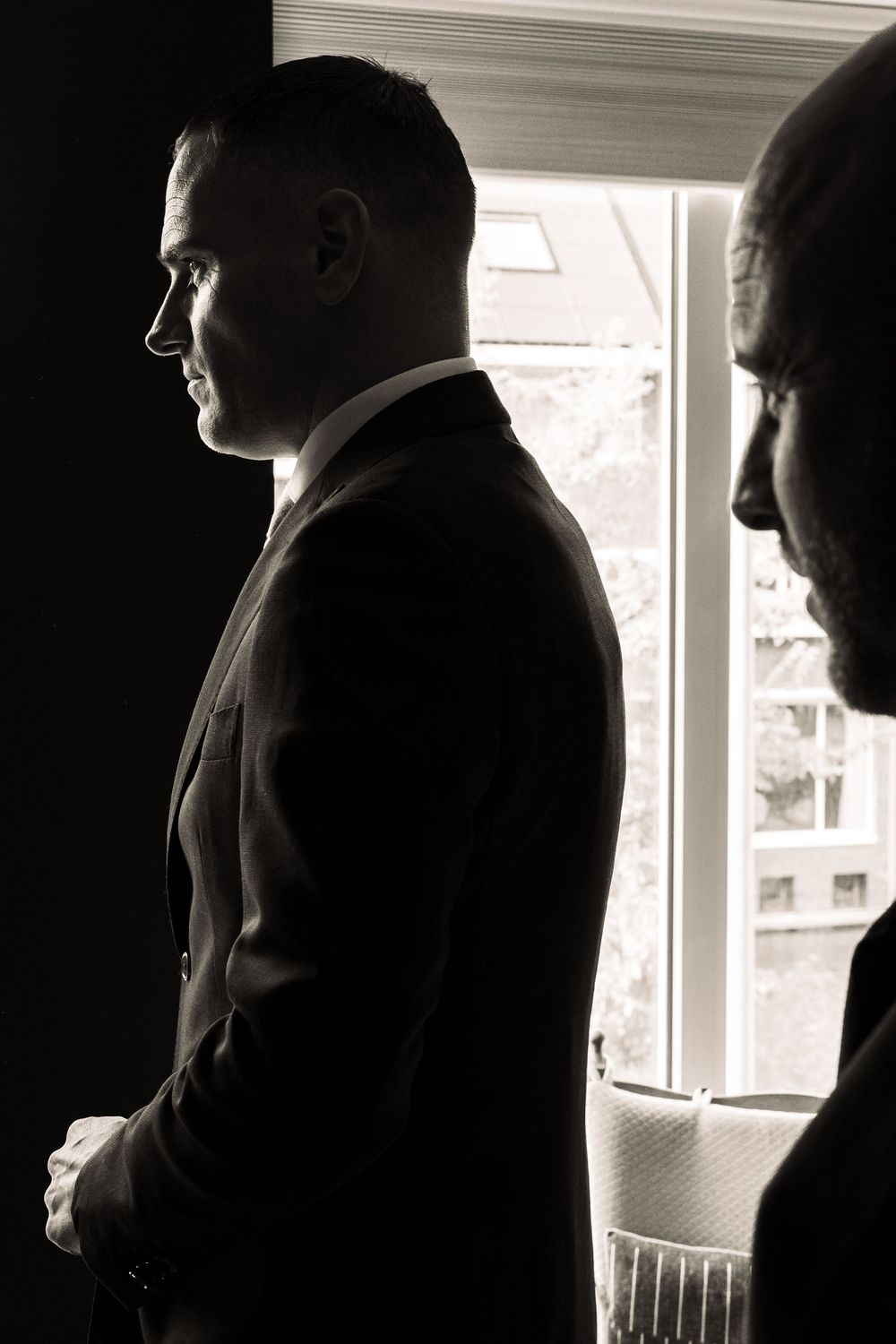 A dramatic black and white silhouette of two figures standing by a bright window.