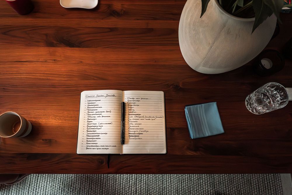 Notebook and coffee cup on wooden table with minimalist styling.