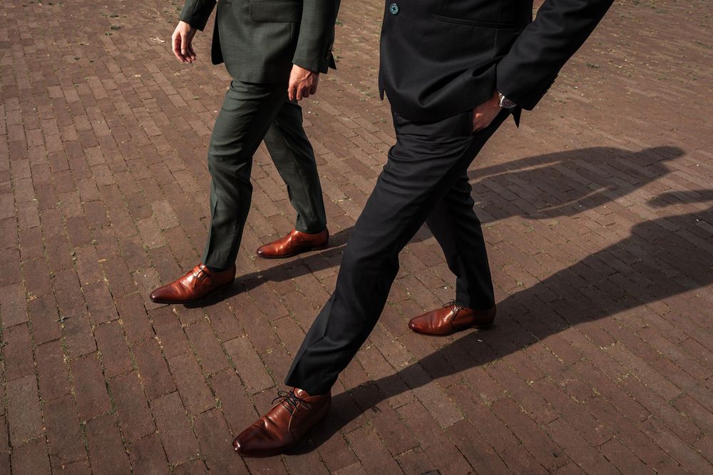 Low angle shots of formal shoes and legs walking on brick pavement.