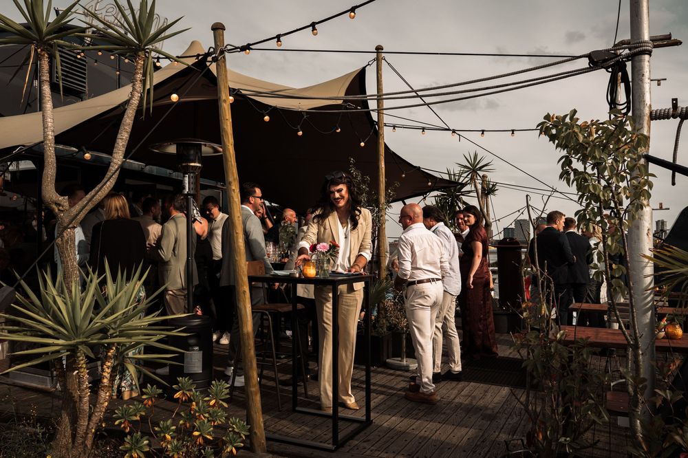 Panoramic view of an outdoor wedding reception with string lights and desert landscaping.