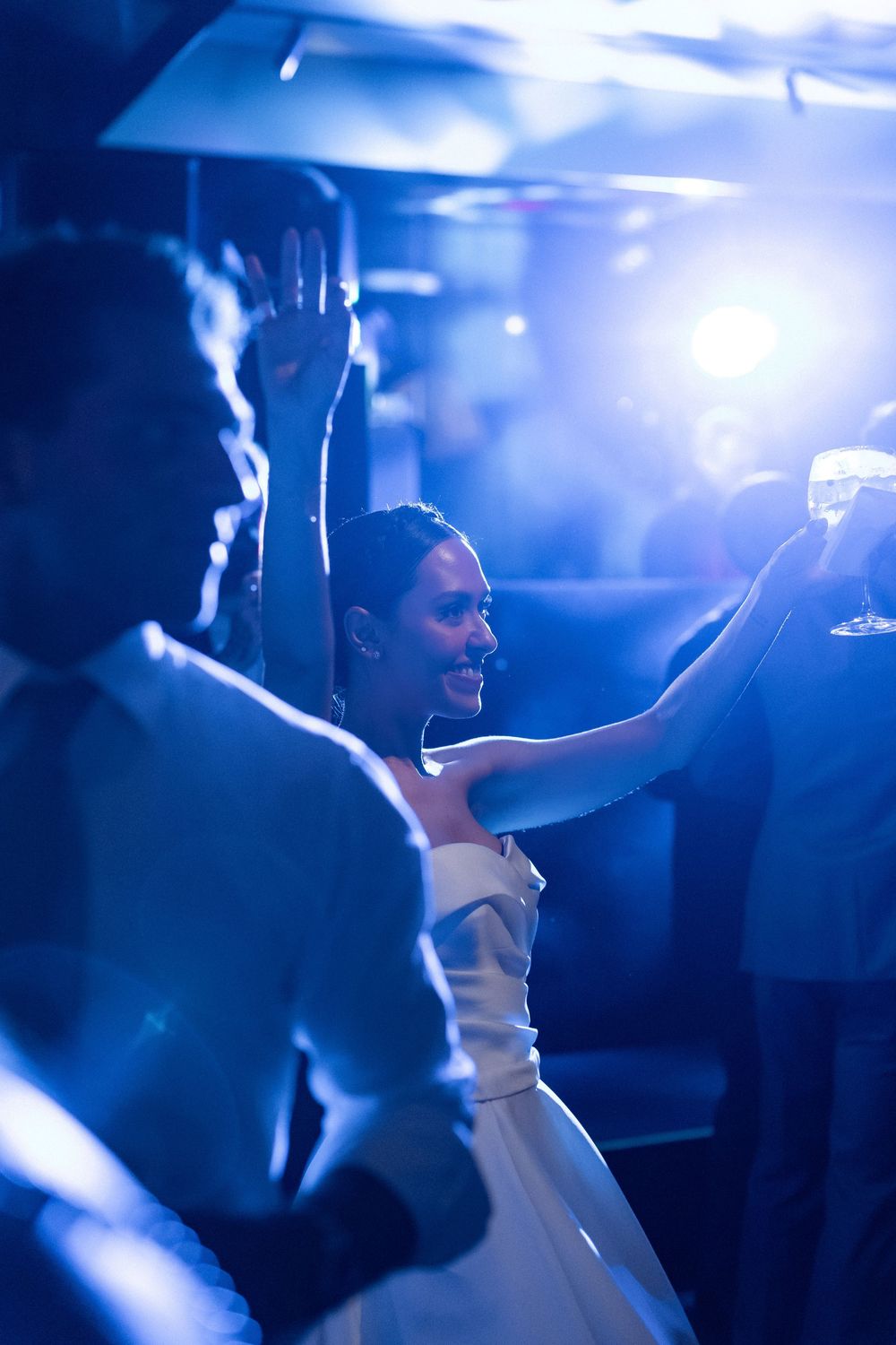 A wedding couple dances together in dramatic blue lighting at their reception celebration.