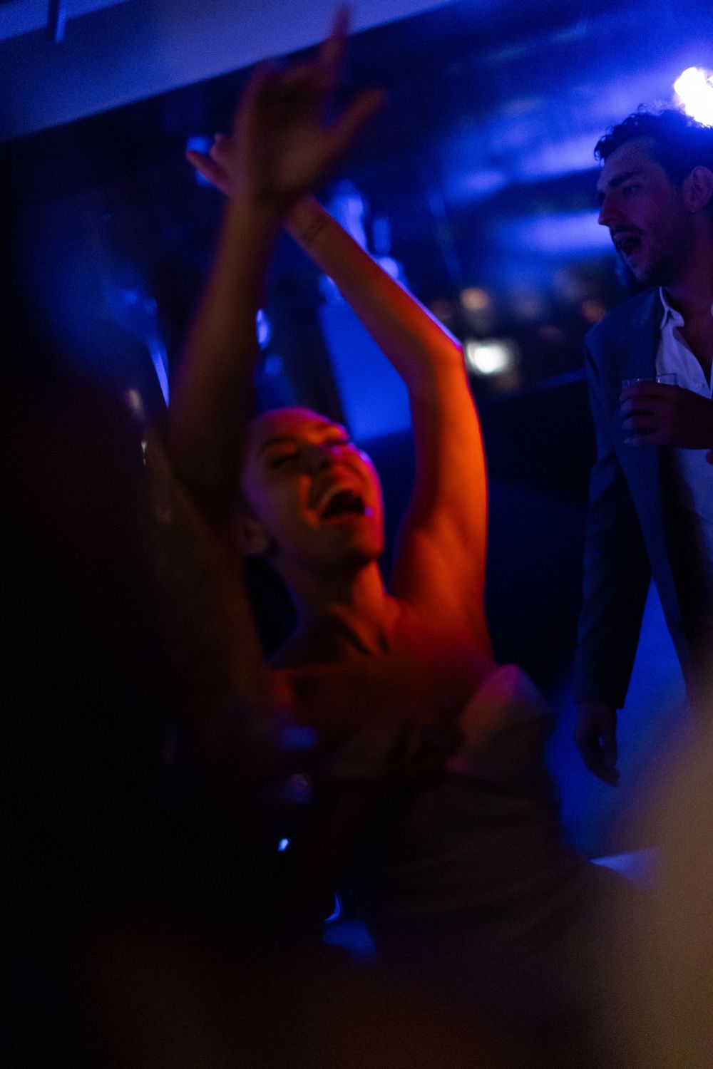 Silhouettes of people dancing in a dark room with blue and orange lighting effects.