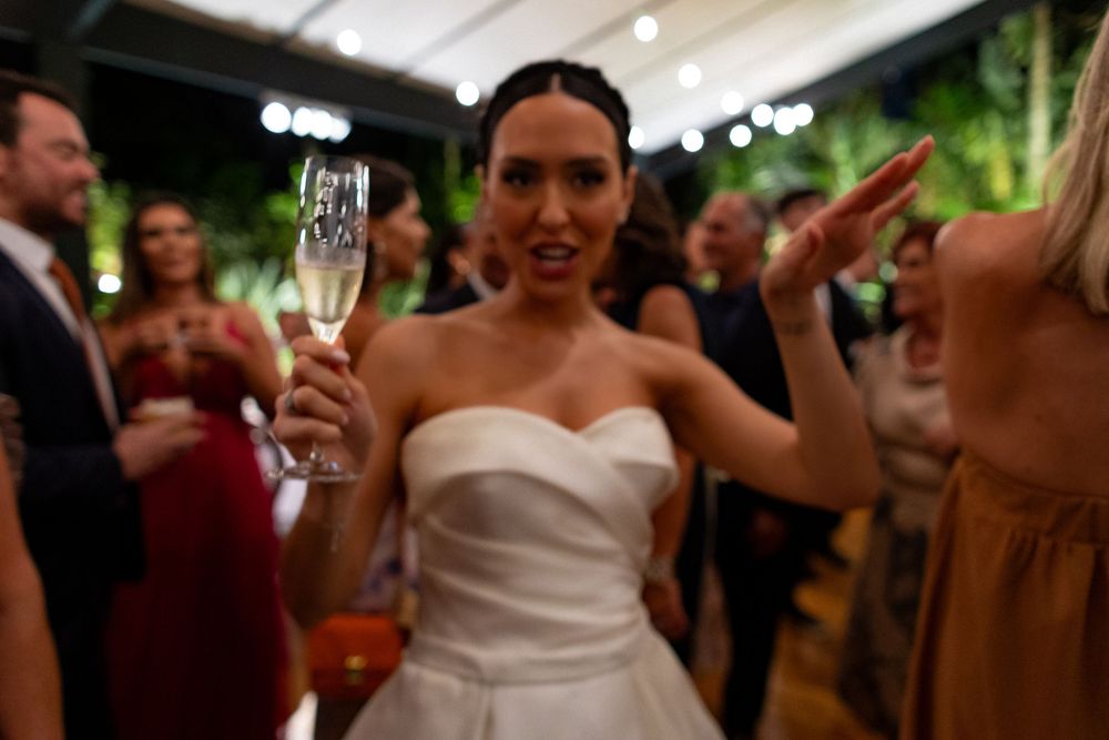 Wedding guests dance and celebrate together on a festive dance floor under string lights at an outdoor reception.